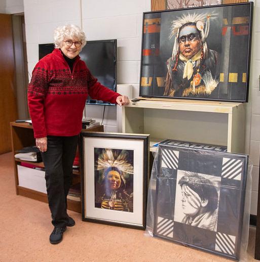 woman with glasses standing by paintings