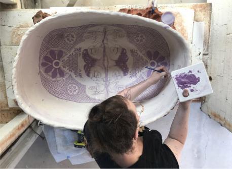 woman painting a piece of ceramic art
