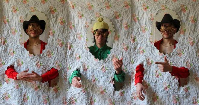 Photo of three men behind fabric, wearing hats and eye masks made of bread.
