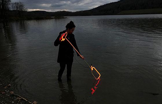 woman stands in lake at dusk with hot glass or neon. 时间流逝