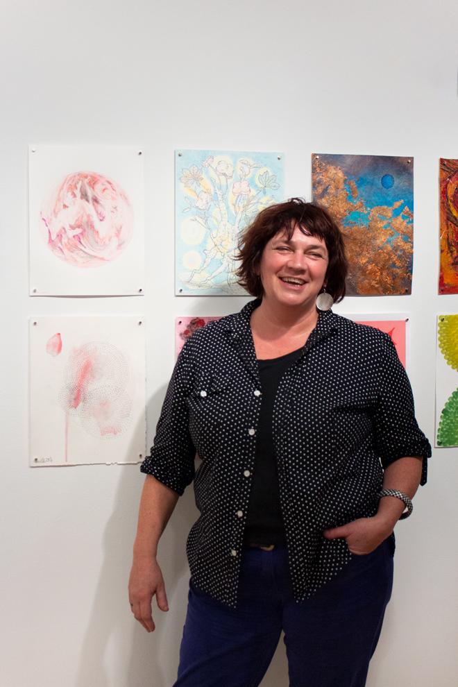 a smiling Coral Lambert posing in front of drawings