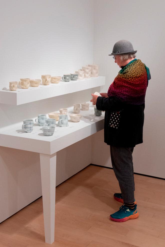 person viewing various pottery on a table